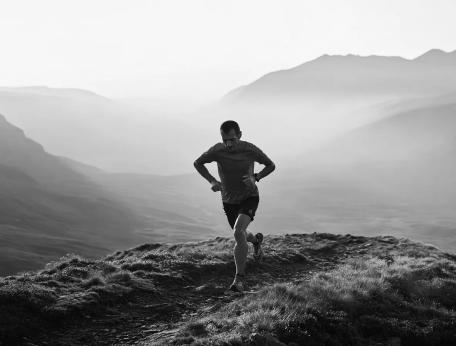 Una persona corriendo en un amplio paisaje de montaña, en blanco y negro